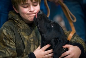 U.S. Air Force photo by Tech. Sgt. Bennie J. Davis III | Brady Rusk, 12, gets a somber kiss from Eli, a bomb-sniffing military working dog, during a retirement and adoption ceremony at Lackland Air Force Base, Texas, Feb. 3, 2011. The Labrador retriever was assigned to Brady’s older brother, Marine Corps Pfc. Colton Rusk, who was killed in Afghanistan.
