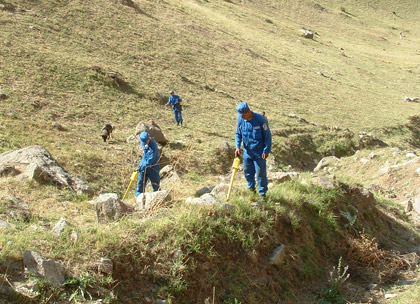 hoto Courtesy of Tajikistan Mine Action Centre | UN deminers, working their way up the mountains, search for buried cluster bombs in Tajikistan.