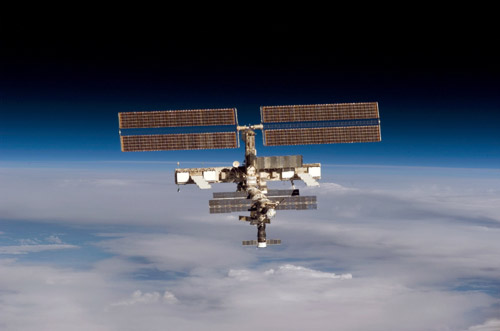 Photo Credit: NASA|Backdropped by the blackness of space and Earth's horizon, the International Space Station moves away from Space Shuttle Discovery.